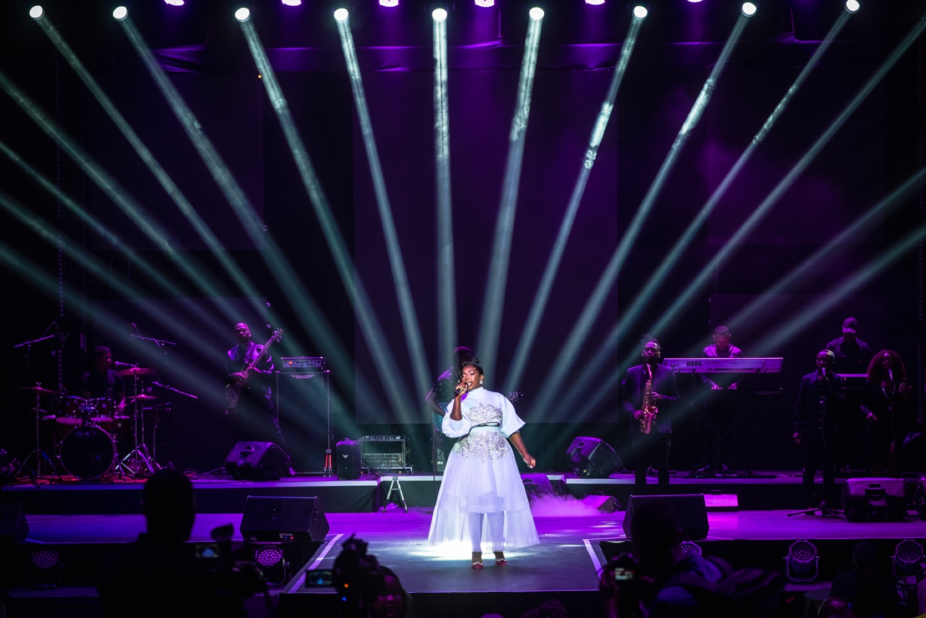 Singer centered beneath dramatic purple and white spotlights