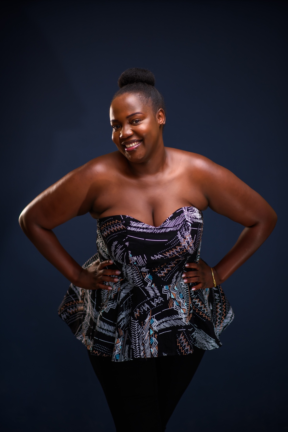 Smiling woman in a patterned outfit against a dark studio backdrop