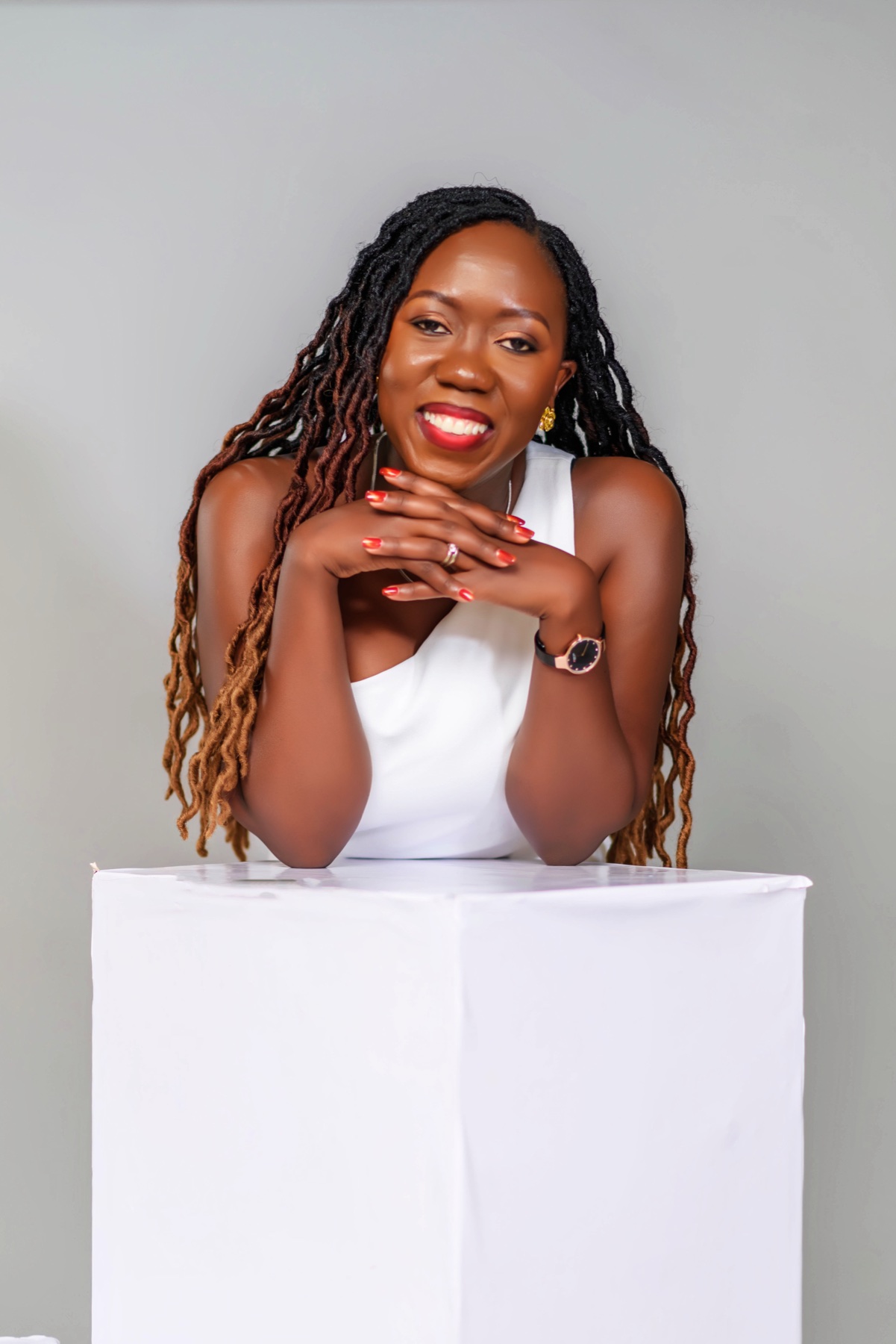 Smiling woman leaning on a white studio plinth